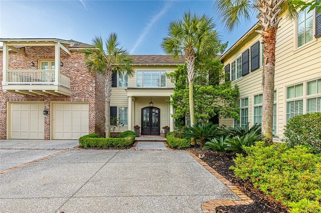 view of front of home featuring a garage, a balcony, and french doors