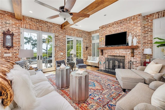 living room featuring french doors, ceiling fan, a fireplace, beamed ceiling, and brick wall