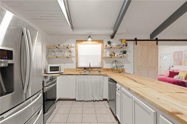 165 Pine Cir, Brunswick, GA 31520 - kitchen featuring stainless steel appliances, open shelves, light tile patterned floors, butcher block counters, and a barn door