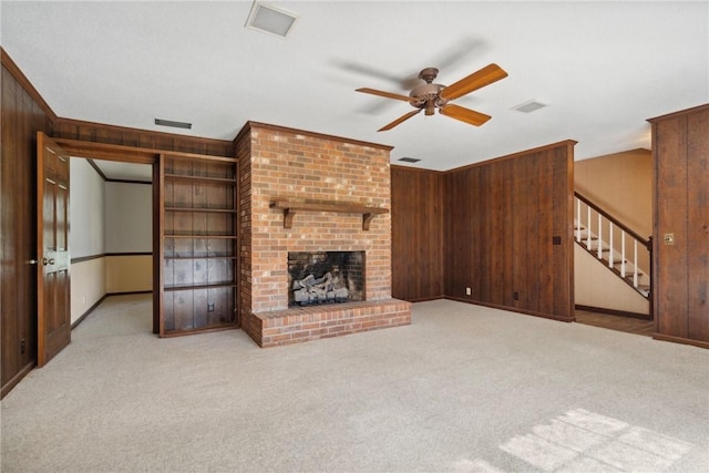 unfurnished living room featuring a fireplace, light carpet, and wooden walls