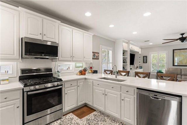 149 Harbor Pointe Dr, Brunswick, GA 31523 - kitchen featuring stainless steel appliances, a sink, open floor plan, ornamental molding, and white cabinets