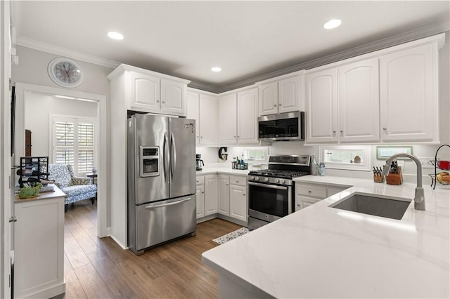 149 Harbor Pointe Dr, Brunswick, GA 31523 - kitchen featuring appliances with stainless steel finishes, a sink, crown molding, white cabinetry, and wood finished floors