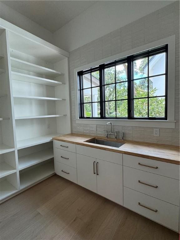 104 Point Ln, Saint Simons Island, GA 31522 - kitchen with a sink, wood finished floors, open shelves, decorative backsplash, and white cabinets
