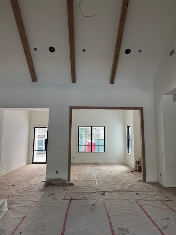 unfurnished living room with beamed ceiling and high vaulted ceiling