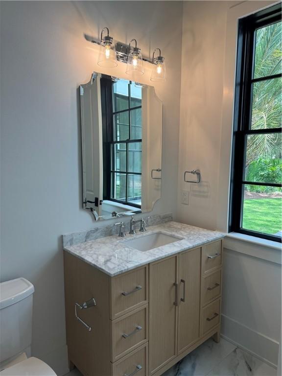104 Point Ln, Saint Simons Island, GA 31522 - bathroom featuring vanity, marble look tiles, and toilet