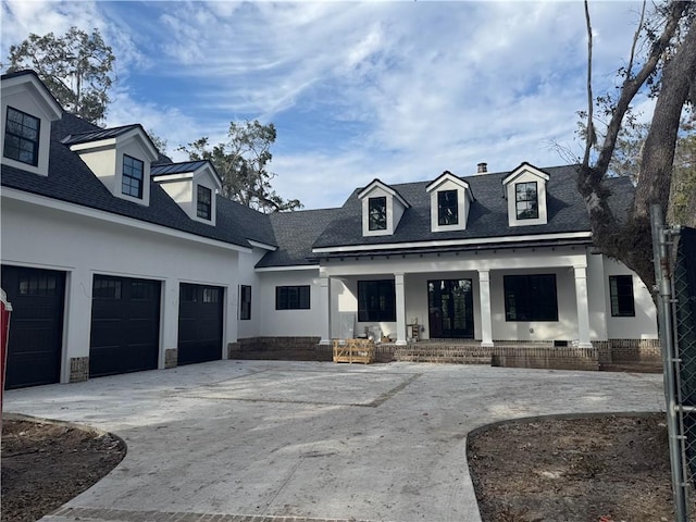cape cod home with stucco siding, driveway, a porch, and roof with shingles