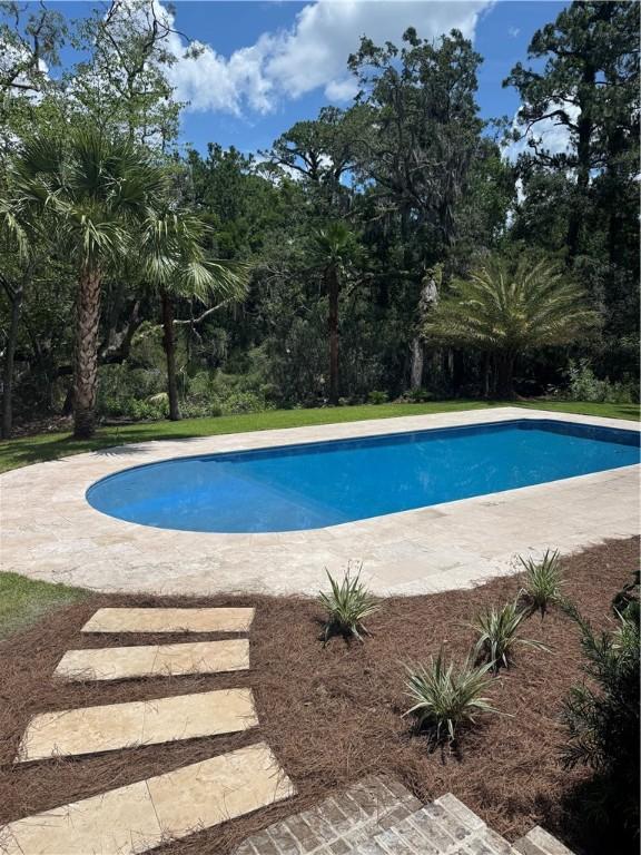 104 Point Ln, Saint Simons Island, GA 31522 - outdoor pool featuring view of scattered trees and a patio