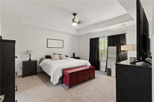 carpeted bedroom with a tray ceiling and ceiling fan