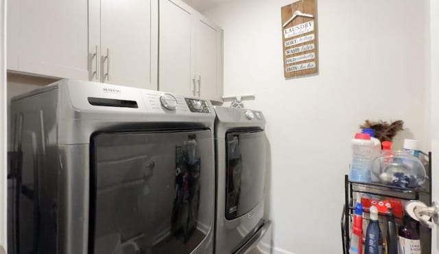 clothes washing area with cabinets and washing machine and clothes dryer