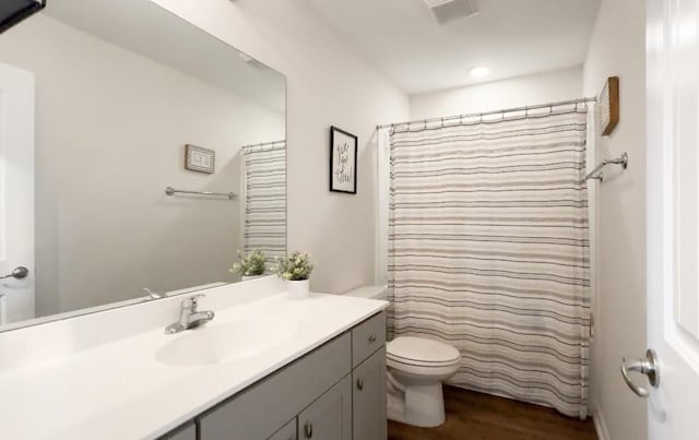 bathroom featuring hardwood / wood-style floors, vanity, toilet, and walk in shower