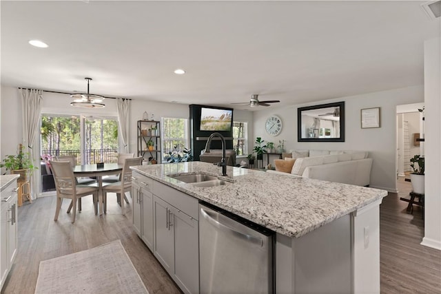 kitchen featuring dishwasher, sink, decorative light fixtures, a center island with sink, and ceiling fan with notable chandelier