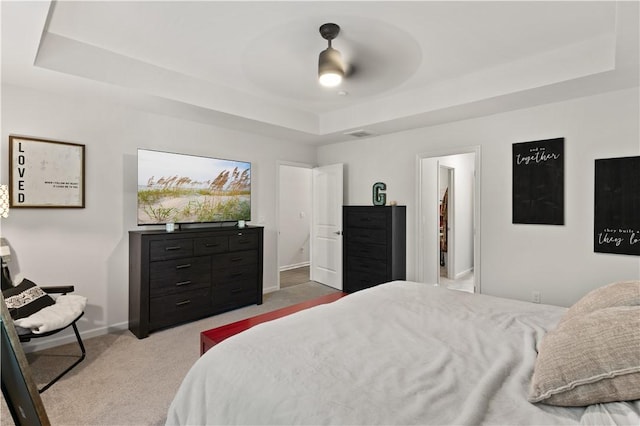 bedroom with carpet floors, a raised ceiling, and ceiling fan