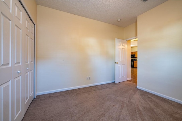 unfurnished bedroom with carpet, a textured ceiling, and a closet