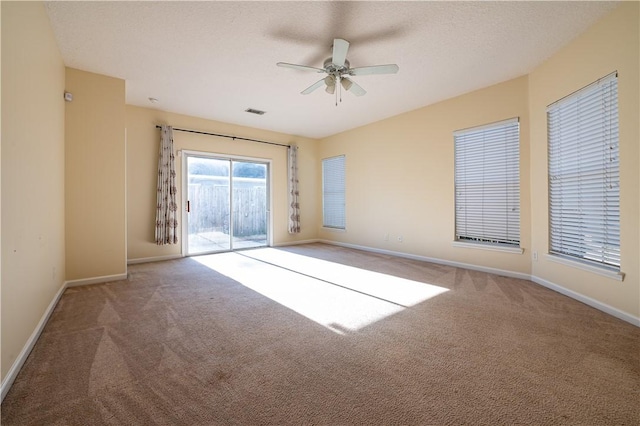 empty room with ceiling fan, carpet floors, and a textured ceiling