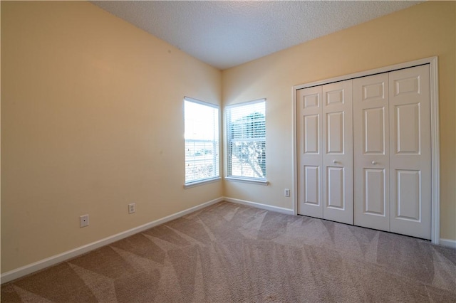 unfurnished bedroom featuring light colored carpet, a textured ceiling, and a closet