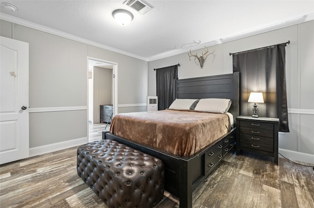 bedroom with dark wood-type flooring, a textured ceiling, and ornamental molding