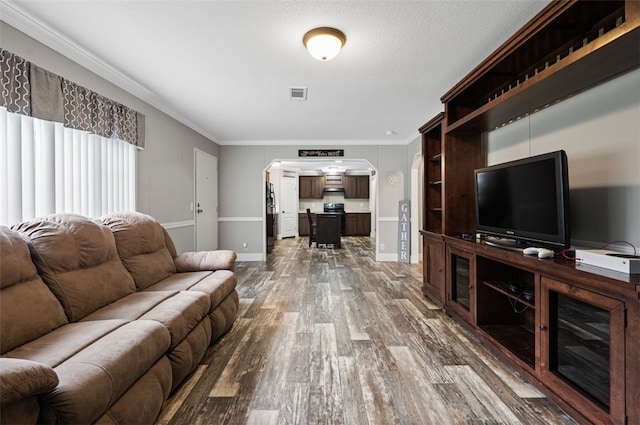 living room with ornamental molding, a textured ceiling, and dark wood-type flooring