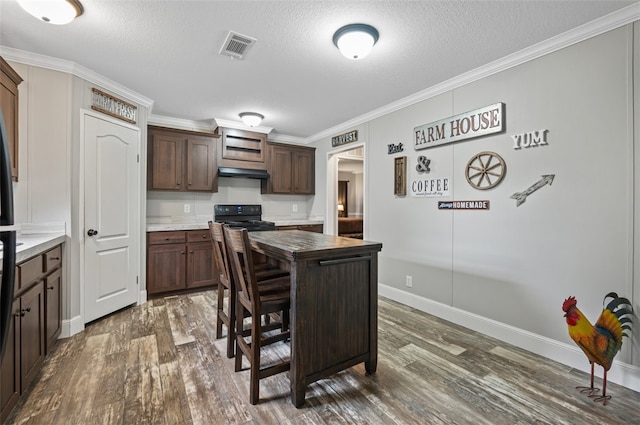 kitchen with a kitchen bar, ornamental molding, dark brown cabinetry, dark hardwood / wood-style floors, and a kitchen island