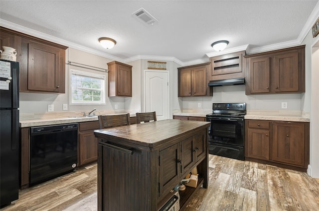 kitchen featuring dark brown cabinetry, light hardwood / wood-style floors, crown molding, and black appliances