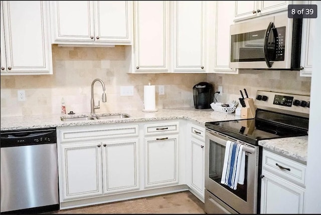 801 Mariners Cir, Saint Simons Island, GA 31522 - kitchen featuring appliances with stainless steel finishes, white cabinetry, decorative backsplash, and light stone countertops