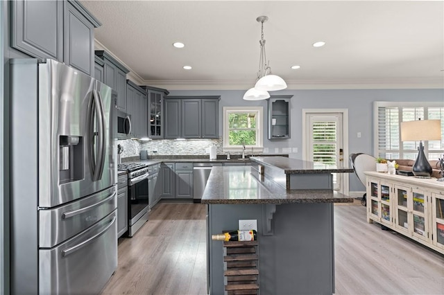 kitchen featuring a center island, pendant lighting, light hardwood / wood-style floors, gray cabinets, and appliances with stainless steel finishes