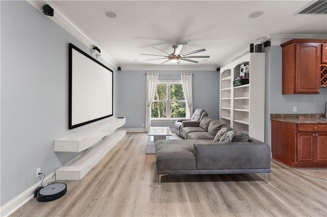 home theater featuring ceiling fan, sink, ornamental molding, and light wood-type flooring