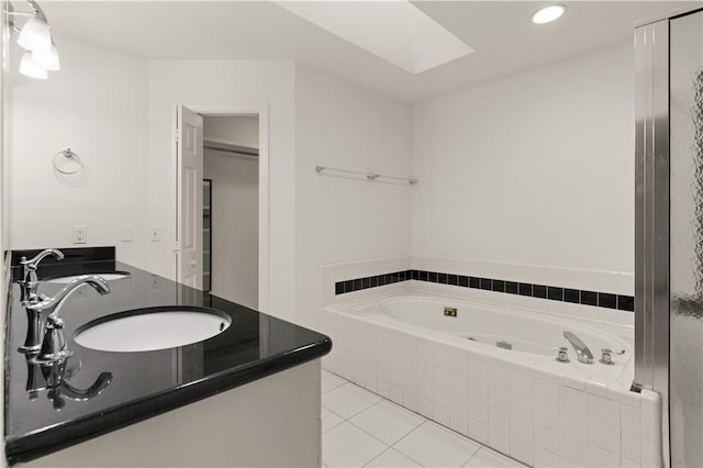 bathroom with tile patterned flooring, vanity, and tiled tub