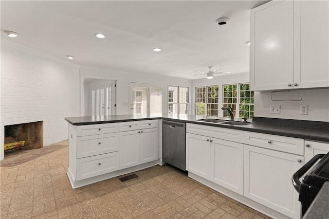 kitchen featuring dishwasher, a brick fireplace, kitchen peninsula, and white cabinets