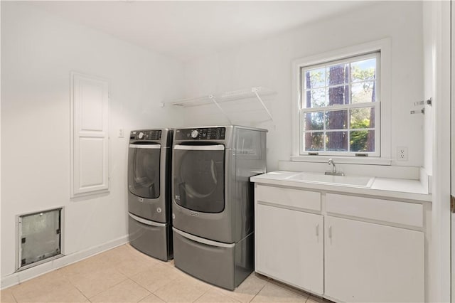 washroom with cabinets, washing machine and dryer, light tile patterned floors, and sink