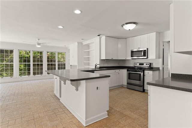 kitchen with sink, kitchen peninsula, ceiling fan, white cabinetry, and stainless steel appliances