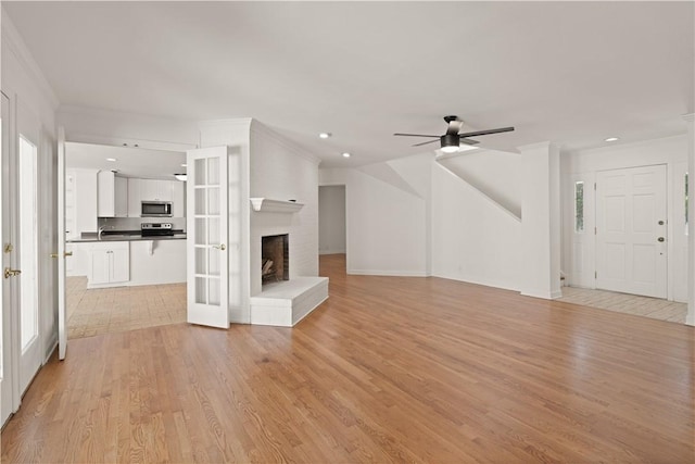 unfurnished living room with french doors, light wood-type flooring, ceiling fan, and crown molding