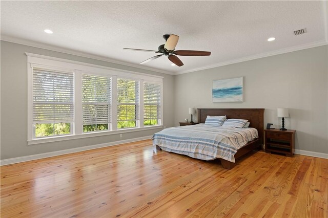 bedroom featuring ceiling fan, light hardwood / wood-style floors, a textured ceiling, and ornamental molding