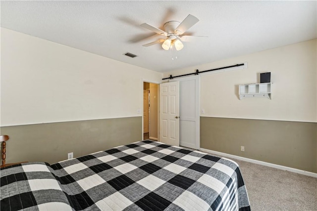 unfurnished bedroom with carpet, ceiling fan, and a barn door