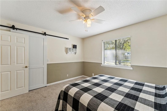 146 Sherwood Forest Cir, Brunswick, GA 31525 - bedroom with a barn door, carpet flooring, a textured ceiling, a ceiling fan, and baseboards