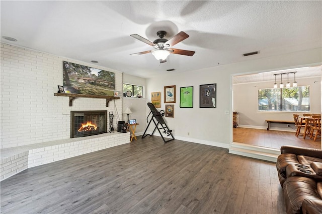 workout area with ceiling fan, a healthy amount of sunlight, dark hardwood / wood-style flooring, and a fireplace