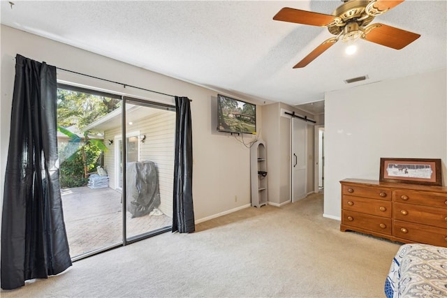 carpeted bedroom featuring access to exterior, ceiling fan, a textured ceiling, and a barn door