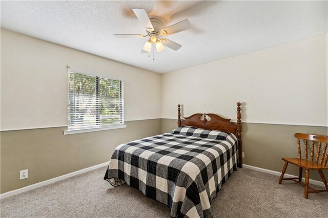 bedroom with ceiling fan, carpet floors, and a textured ceiling