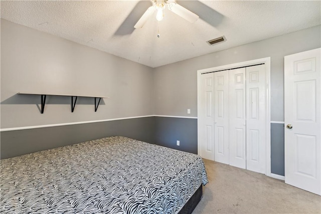 bedroom with light carpet, a closet, ceiling fan, and a textured ceiling