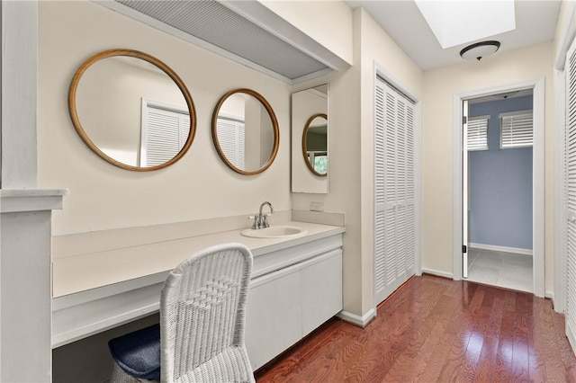 893 Wimbledon Dr, Saint Simons Island, GA 31522 - bathroom featuring vanity, wood finished floors, baseboards, a skylight, and a closet