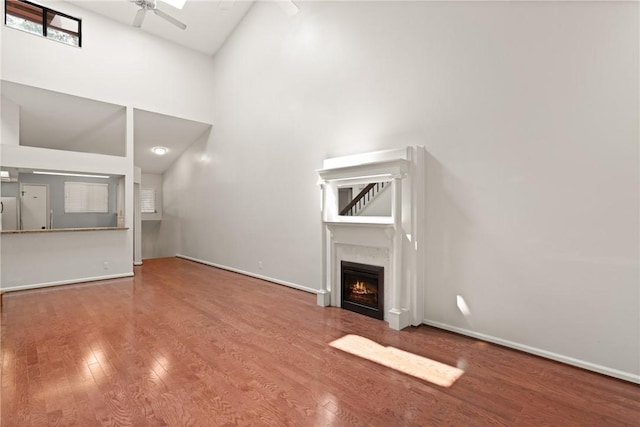 893 Wimbledon Dr, Saint Simons Island, GA 31522 - unfurnished living room with a ceiling fan, high vaulted ceiling, wood finished floors, baseboards, and a lit fireplace