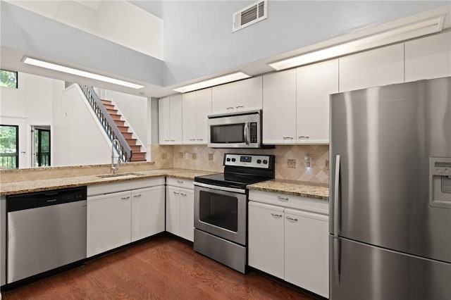 893 Wimbledon Dr, Saint Simons Island, GA 31522 - kitchen with stainless steel appliances, a sink, white cabinetry, dark wood-style floors, and backsplash