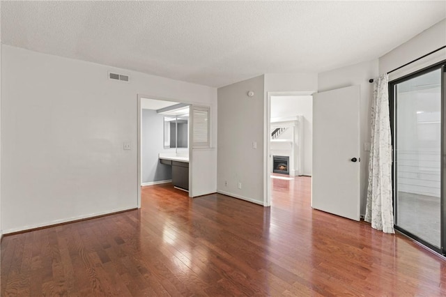 893 Wimbledon Dr, Saint Simons Island, GA 31522 - unfurnished room with wood finished floors, a textured ceiling, a fireplace, and baseboards