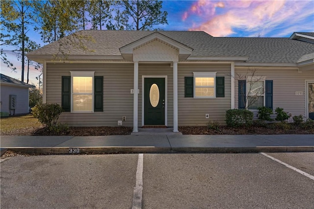 view of front of property featuring uncovered parking and roof with shingles