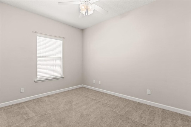 carpeted empty room featuring baseboards and a ceiling fan