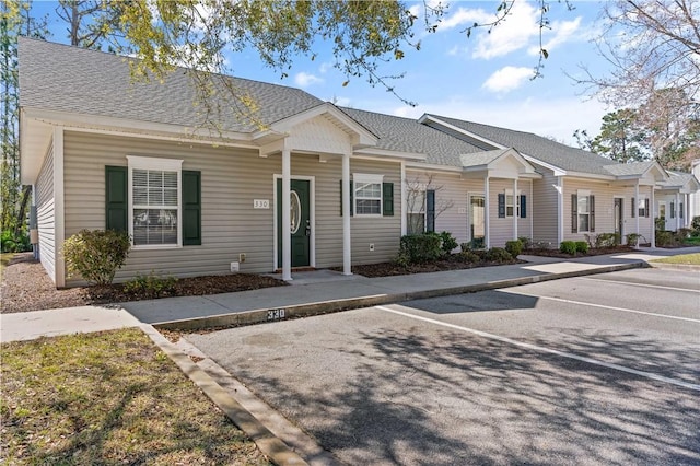 townhome / multi-family property with a shingled roof and uncovered parking