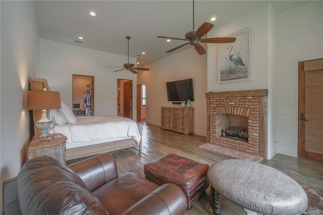 bedroom featuring a spacious closet, ceiling fan, light wood-type flooring, and a fireplace