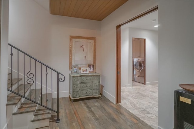 stairs with washer / clothes dryer, hardwood / wood-style floors, and wooden ceiling