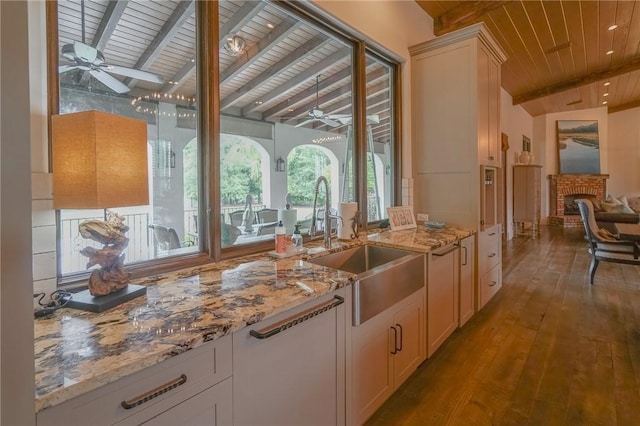 bar featuring light wood-type flooring, a brick fireplace, wood ceiling, ceiling fan, and vaulted ceiling with beams