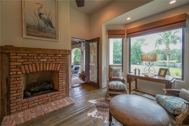 living area featuring wood-type flooring and a brick fireplace