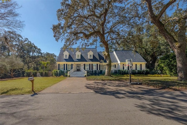 cape cod home featuring a front lawn